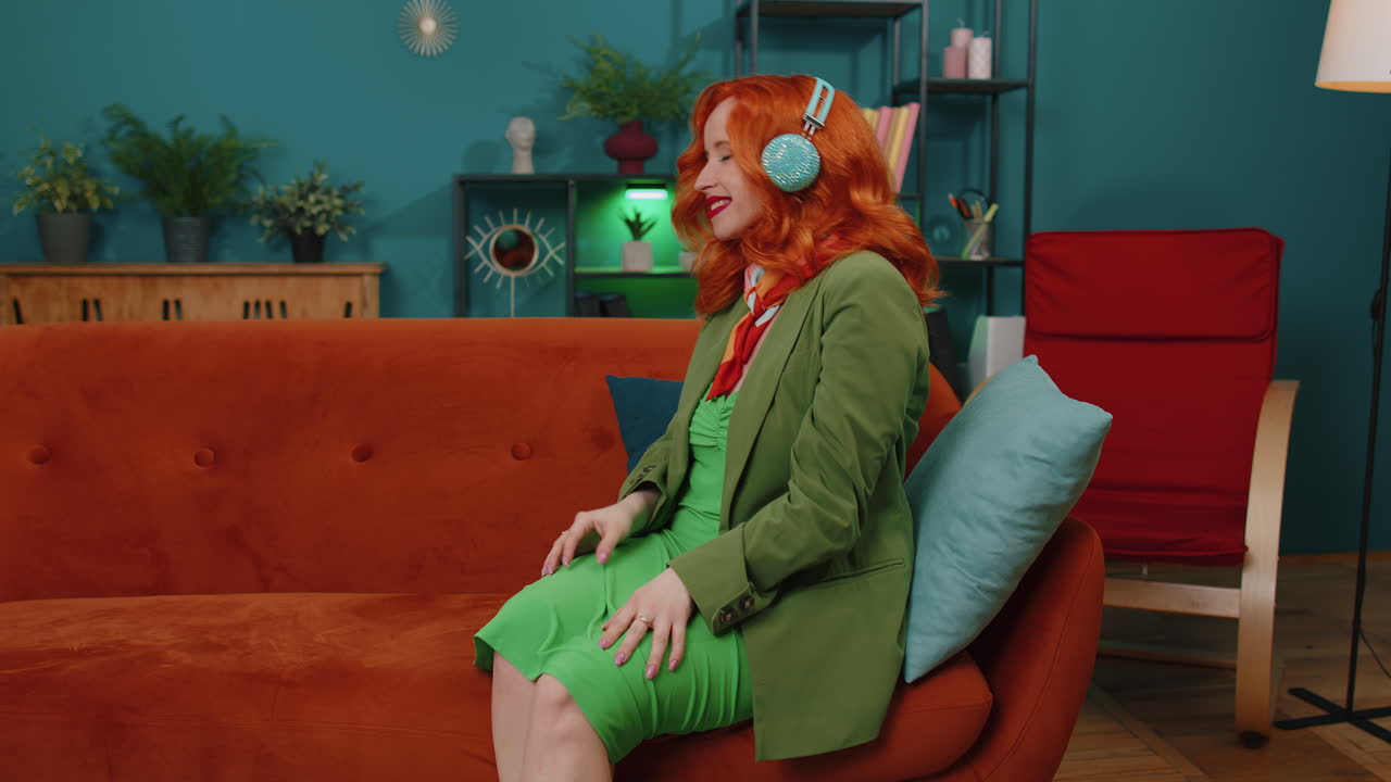 chica feliz y relajada con auriculares inalámbricos bailando escuchando su música rock n roll favorita en el sofá de casa