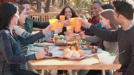 grupo de amigos felices en una mesa al aire libre haciendo un brindis