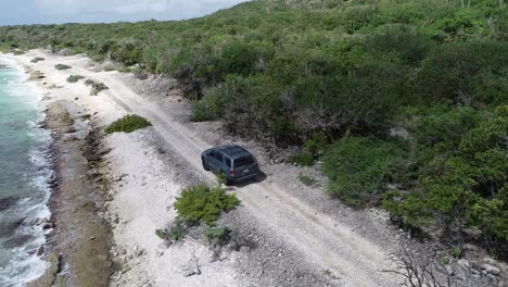 off road car on rocky coral coastline waves crashing with greenery and cacti