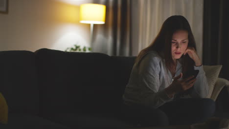 Woman-Sitting-On-Sofa-At-Home-At-Streaming-Or-Watching-Movie-Or-Show-Or-Scrolling-Internet-On-Mobile-Phone-16