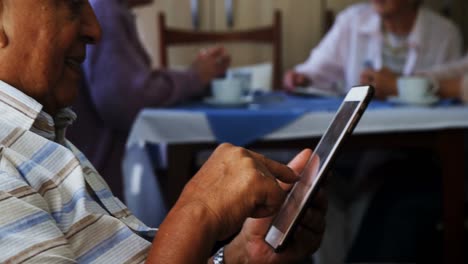 senior man using digital tablet with his friends sitting in background 4k