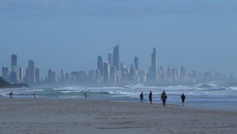 people walking at the shore of palm beach - surfers paradise skyscrapers - gold coast, queensland, australia