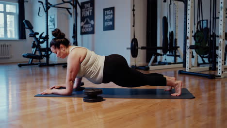 plus size woman doing plank exercise in gym