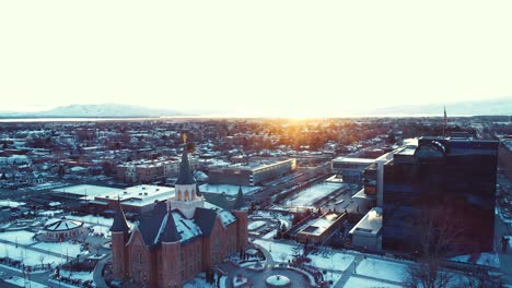 Antenne-Des-Tempels-Im-Stadtzentrum-Von-Provo-Bei-Sonnenuntergang-Und-Sonnenaufgang-Mit-Einem-Leuchtend-Orangefarbenen-Sonnenstrahl-über-Der-Stadt-Provo,-Utah