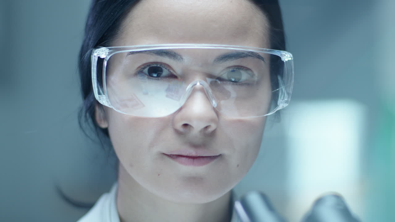Portrait of Female Microbiologist Wearing Protective Glasses in Laboratory