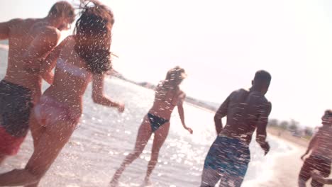 young multi-ethnic friends running on the beach in summer