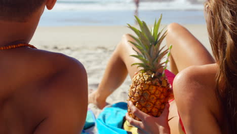 una pareja relajándose en la playa con una bebida de piña.