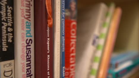 a closeup dolly shot tracking along a library bookshelf, the titles visible on the spine of the respective books