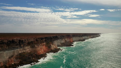 Vista-Aérea-De-Las-Olas-Rompiendo-En-Un-Acantilado-Escarpado,-Hermosa-Gama-De-Colores-En-Australia