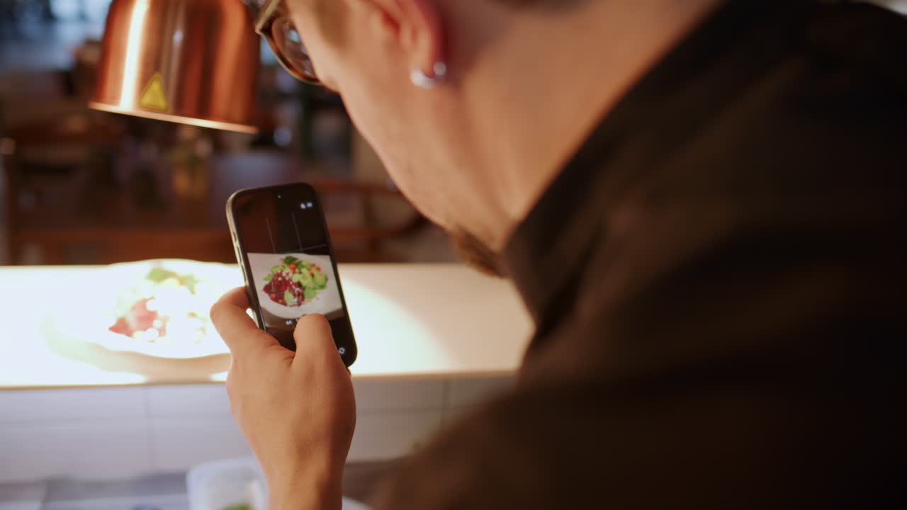 Chef Photographing Gourmet Dish with Smartphone in Restaurant Kitchen