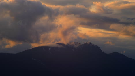 nubes rodando sobre el pico de la montaña durante la puesta de sol - lapso de tiempo