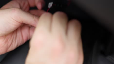 two hands carefully connecting red and black wires to a small plug and connector, illustrating precise work in electronics or assembly tasks