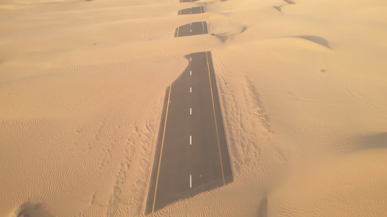 Aerial view from drone of abandoned desert roads covered with sand dunes in Dubai, United Arab Emirates