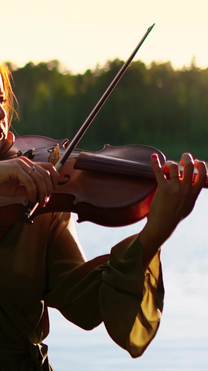 Woman Playing Violin by a Lake at Sunset