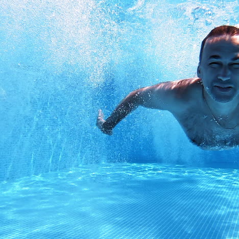 boy and a man jumping into the water. father with a son jump underwater and a man swimming in blue clear water inside the swimming pool.
