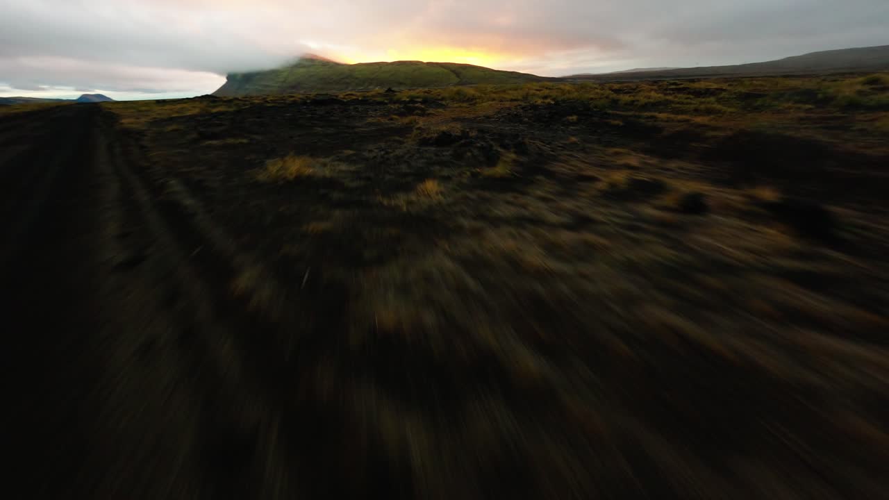 un dron fpv vuela más allá de un suv a través del desolado paisaje de islandia durante la puesta de sol