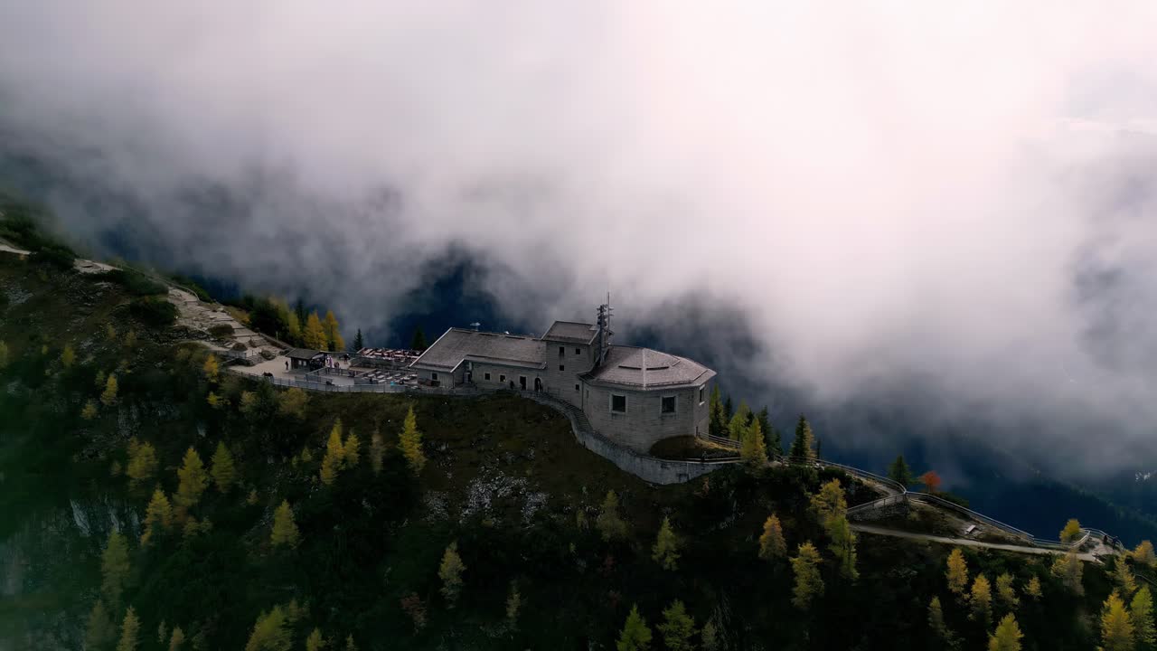 vista aérea de un majestuoso castillo de piedra en lo alto de un pico de montaña, envuelto en niebla