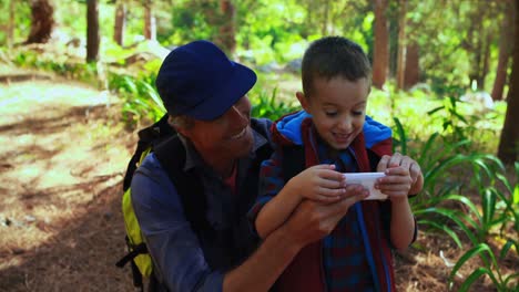 Padre-Ayudando-A-Su-Hijo-A-Usar-Un-Teléfono-Móvil-En-El-Parque