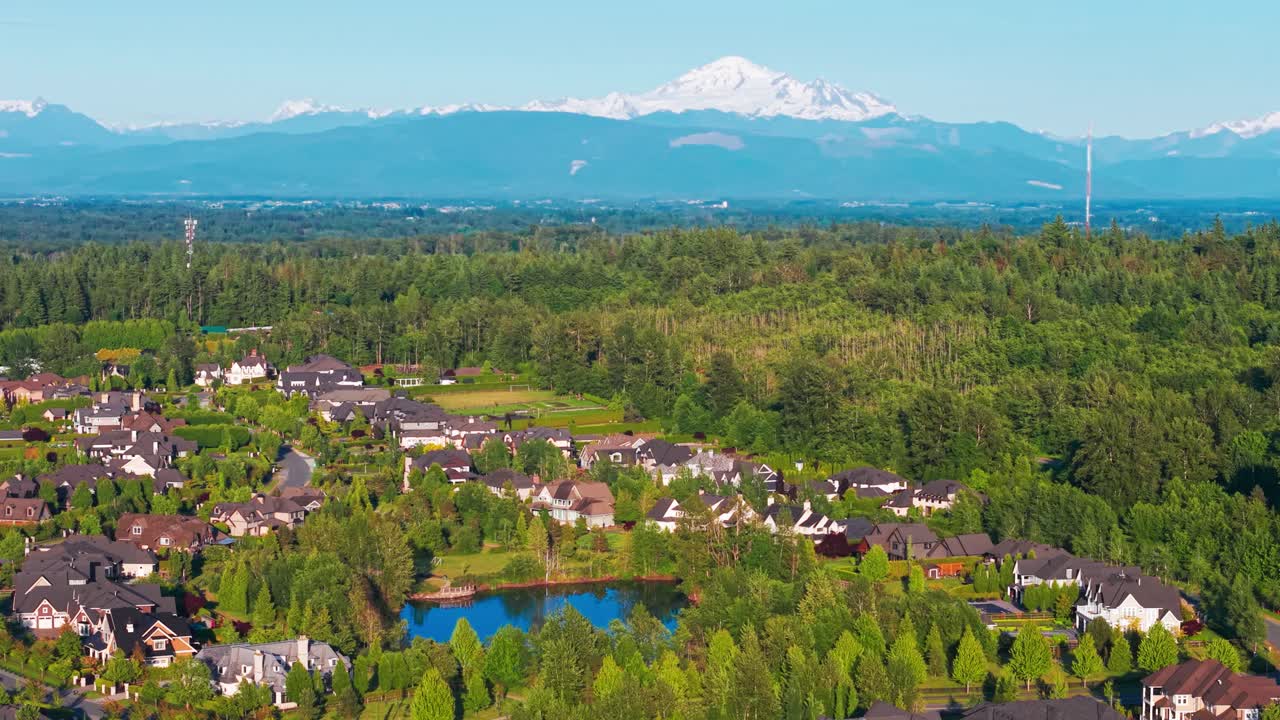 Luxury suburban homes surrounded by lush green trees on a warm sunny day with Mt Baker on the horizon in Langley Township in Canada
