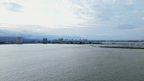 aerial views capture the serene emeryville shoreline where calm waters meet the urban skyline under soft skies. filmed in 4k.