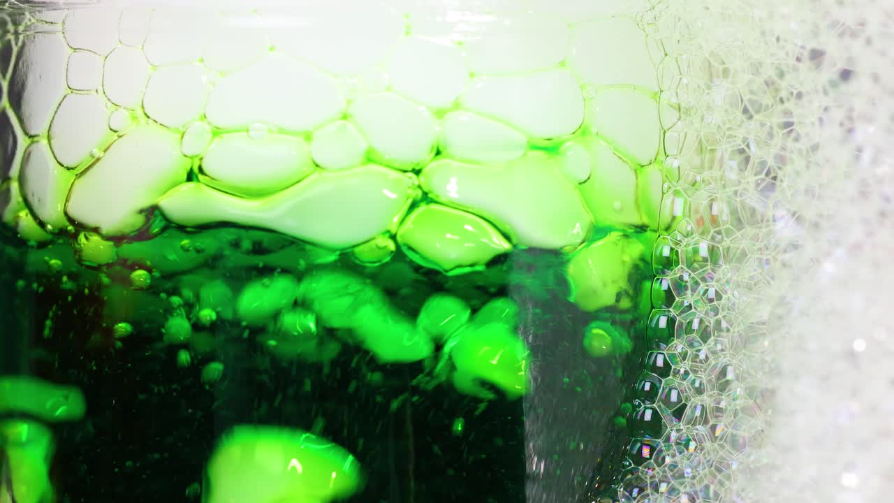 un líquido verde vibrante reacciona con hielo seco, creando burbujas dinámicas y espuma en un experimento científico