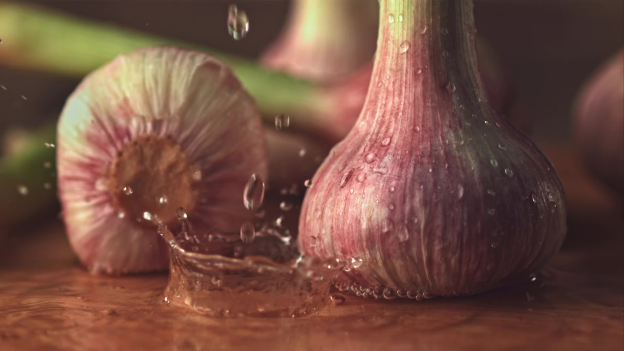 Eau éclaboussant des bulbes d'ail frais au ralenti