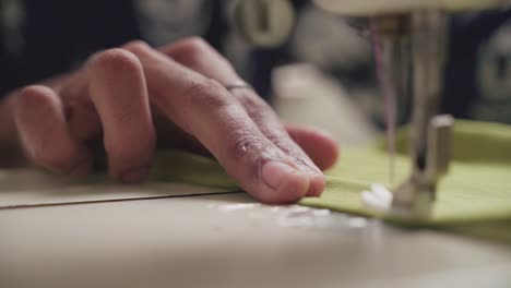 close up of the hands of a tailor using a sewing machine