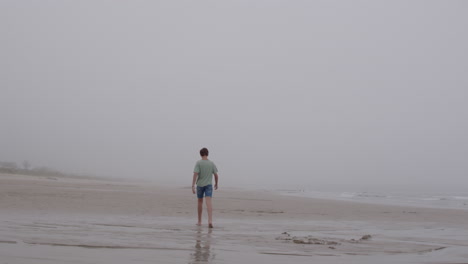 boy walking on a foggy beach