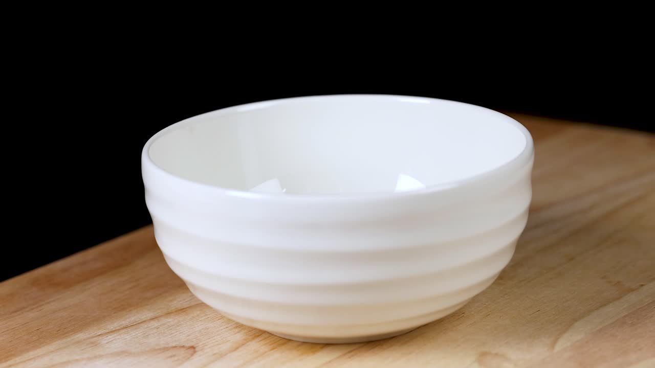 los pedazos de caqui caen en un cuenco blanco