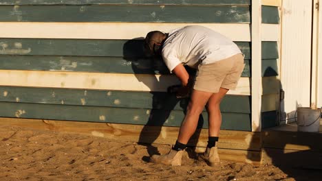 carpenter repairing a beach shed wall