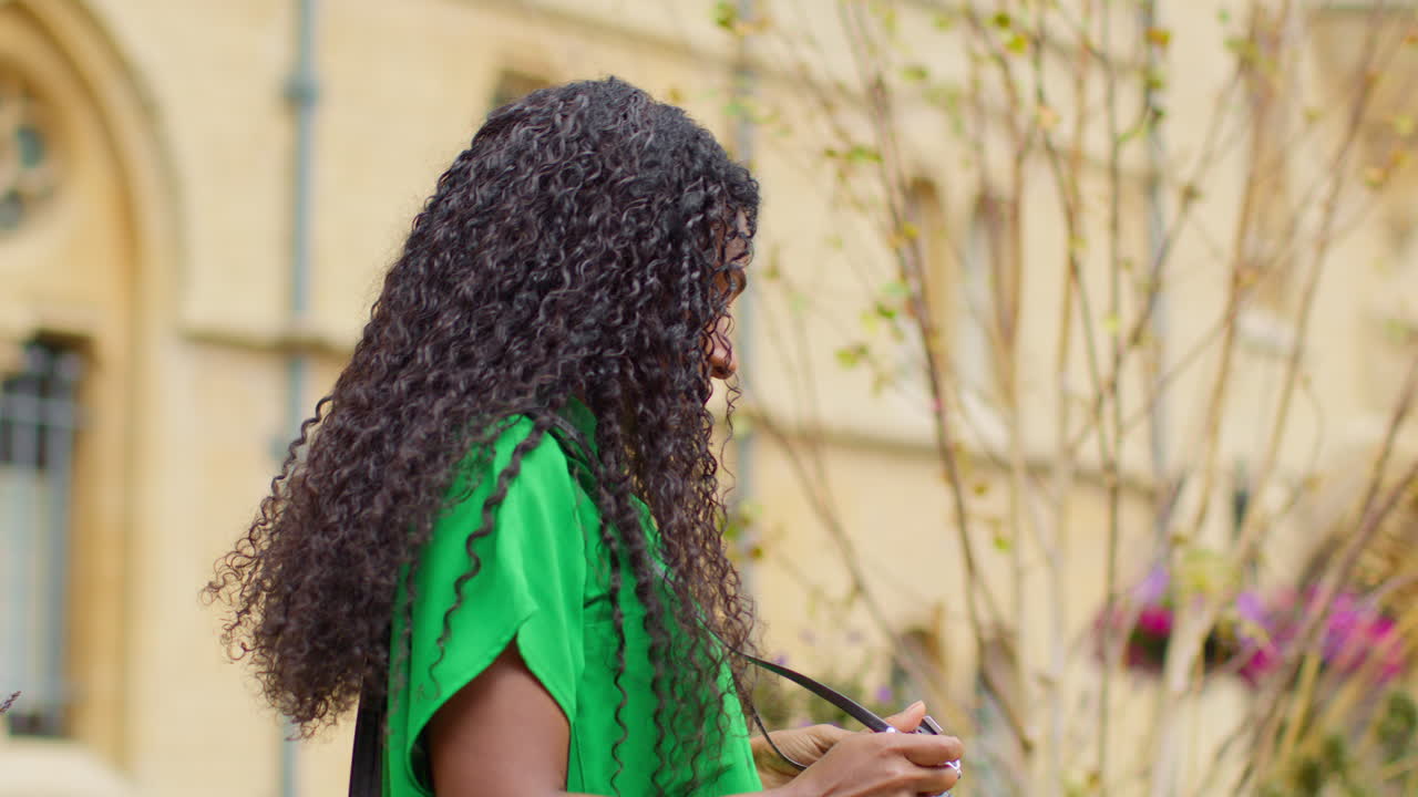 туристка с камерой в отпуске в оксфорде, великобритания, исследует город, гуляет по брод-стрит, делает фотографии.