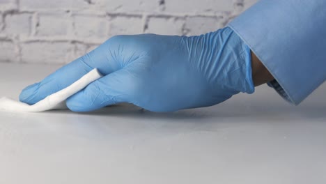 cleaning a surface with a white cloth and blue gloves