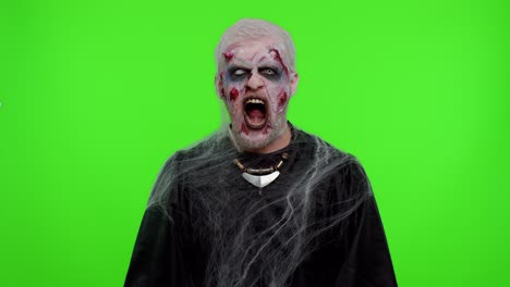 sinister man in costume of halloween crazy zombie with bloody wounded scars face screaming, shouting