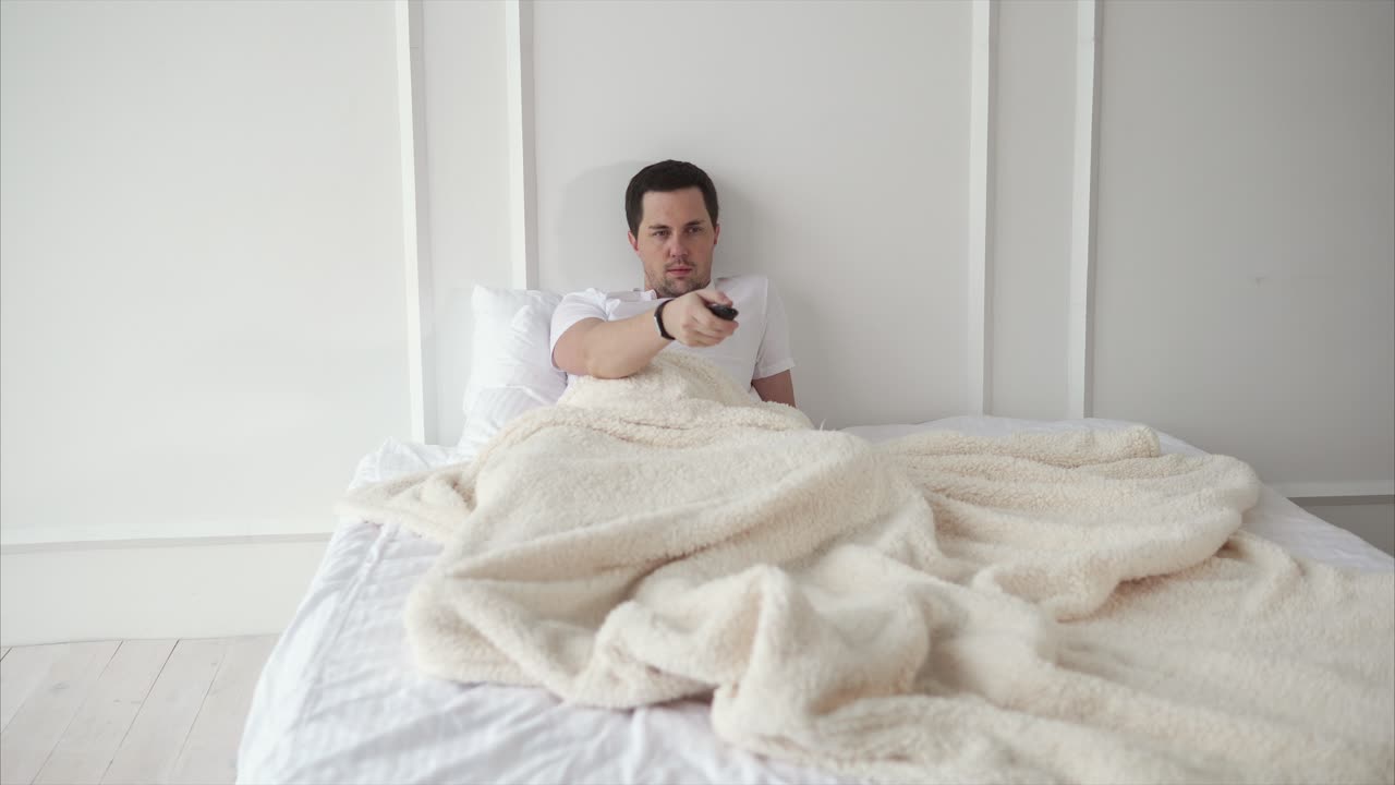 hombre viendo la televisión en la cama