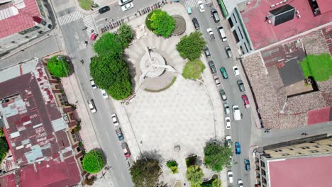 drone zenithal orbit over the central plaza of cobán, guatemala, showing urban symmetry, cars and pedestrians in broad daylight