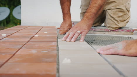 master lays the tiles on the floor puts it on glue close-up