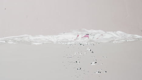 video of beauty product bottle falling into water with copy space on white background