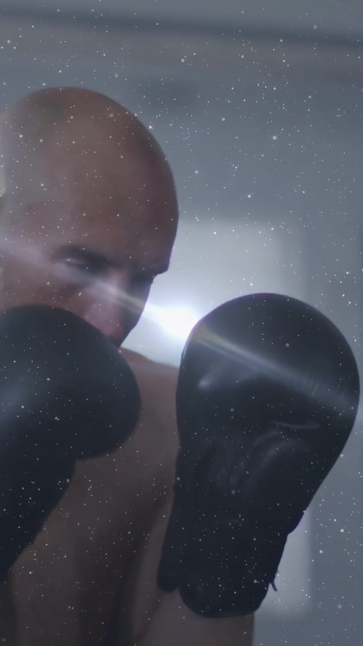 Video verticale: Boxer che inizia l'allenamento, sferra pugni, guantoni con effetto lens flare e sovrapposizione stellata