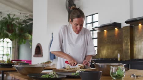 Caucasian-female-chef-preparing-a-dish-and-smiling-in-a-kitchen-