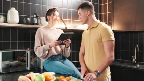 couple in kitchen preparing food with tablet