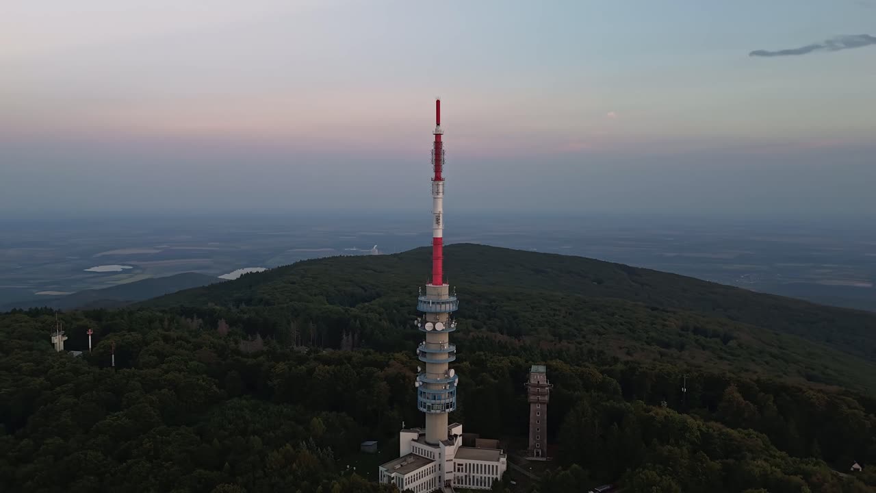 Orbital drone hyperlapse around the Kékes TV Tower with scenic view of the Mátra Mountains at dusk in Hungary