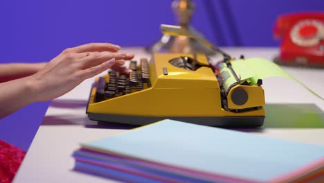 a woman types on a yellow vintage typewriter with green paper. surrounded by pastel sheets and retro props, she works in a vibrant office filled with nostalgic color and creative atmosphere