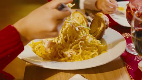 una chica rodando sus espaguetis en una cena.