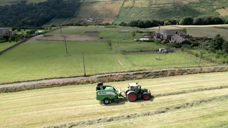 Grüner-Traktor,-Der-Heu-Auf-Einer-Luftaufnahme-Der-Ländlichen-Landschaft-Erntet