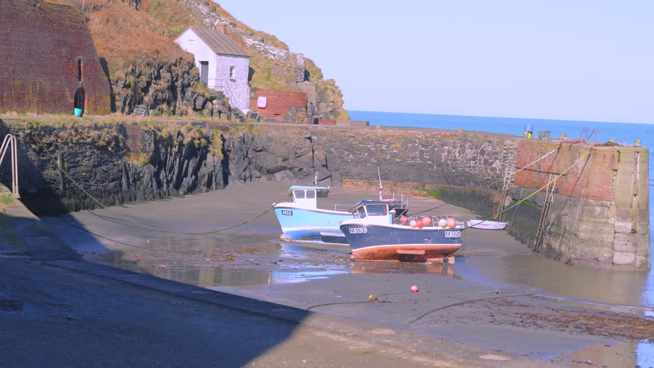 Cute Small Welsh Harbour with Fishing Boats and Old Industrial Slate Mining Building with Cliffs and Blue Sea Water.