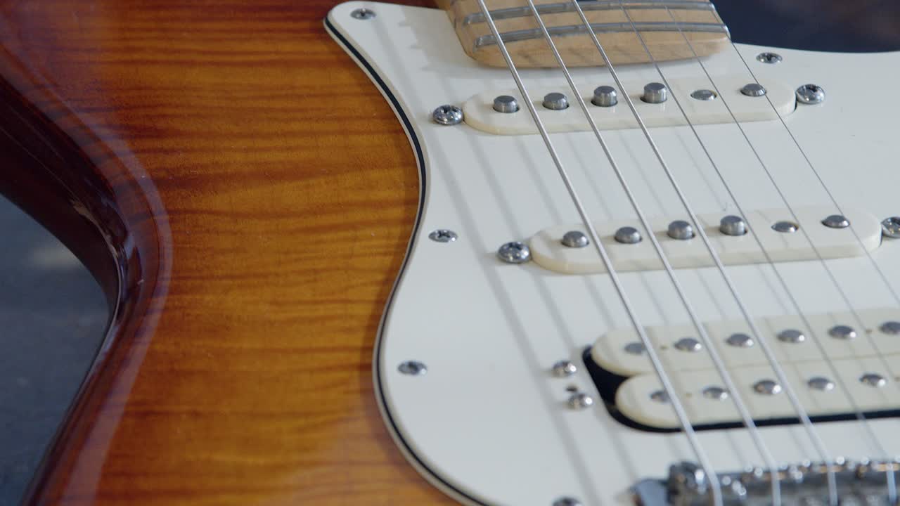 Lenta panoramica dalla tastiera del manico al corpo di una chitarra elettrica in acero fiammato.
