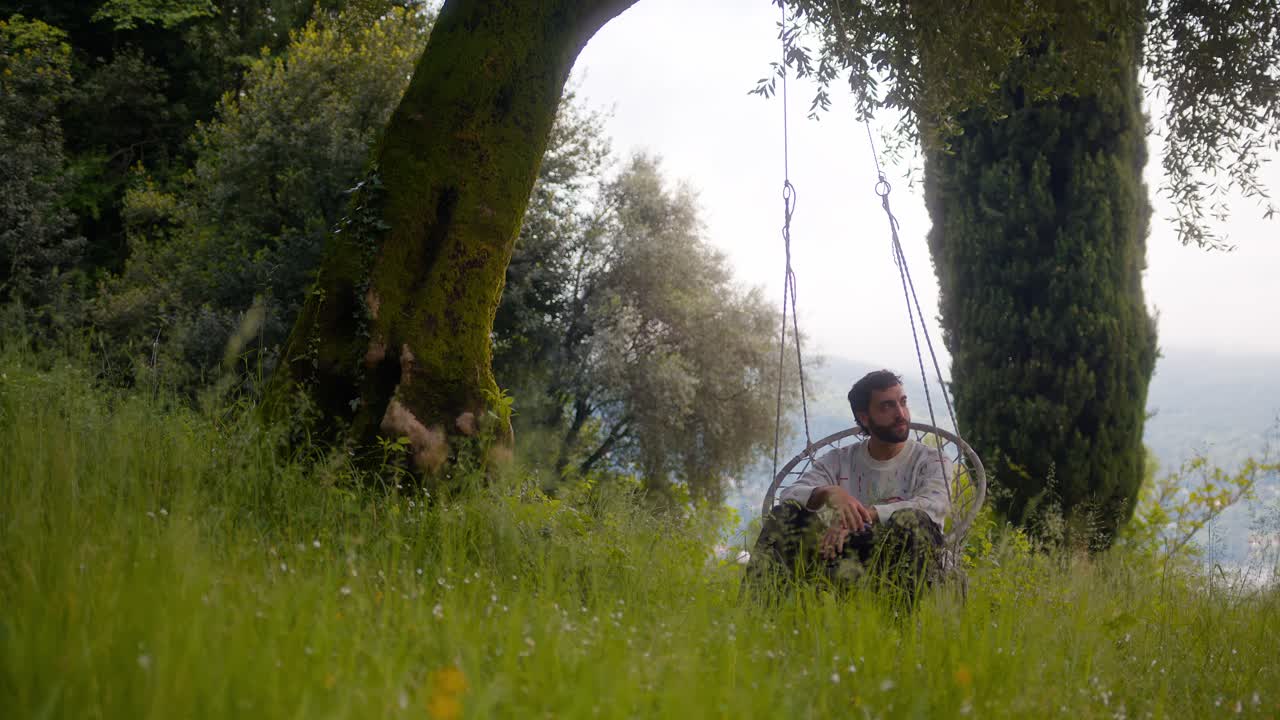 Close-up of man alone on hanging bench in Lake Como, Italy (Lago di Como, Italia), on a calm cloudy day in solitude