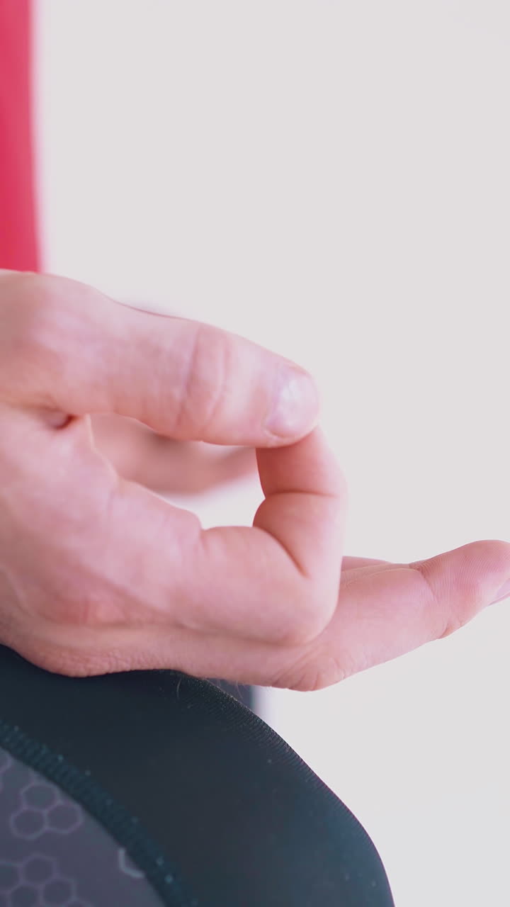 hand with bracelet lies on man leg sitting and meditating in butterfly fly yoga asana in hammock extreme close view