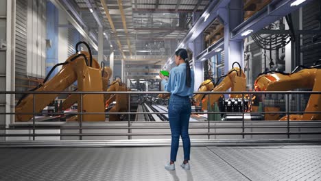 full body back view of asian female with green screen smartphone with industrial robotic arms working, industrial facility