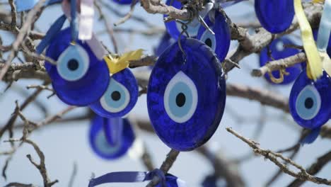 close-up shot of evil eye beads tied to tree branches